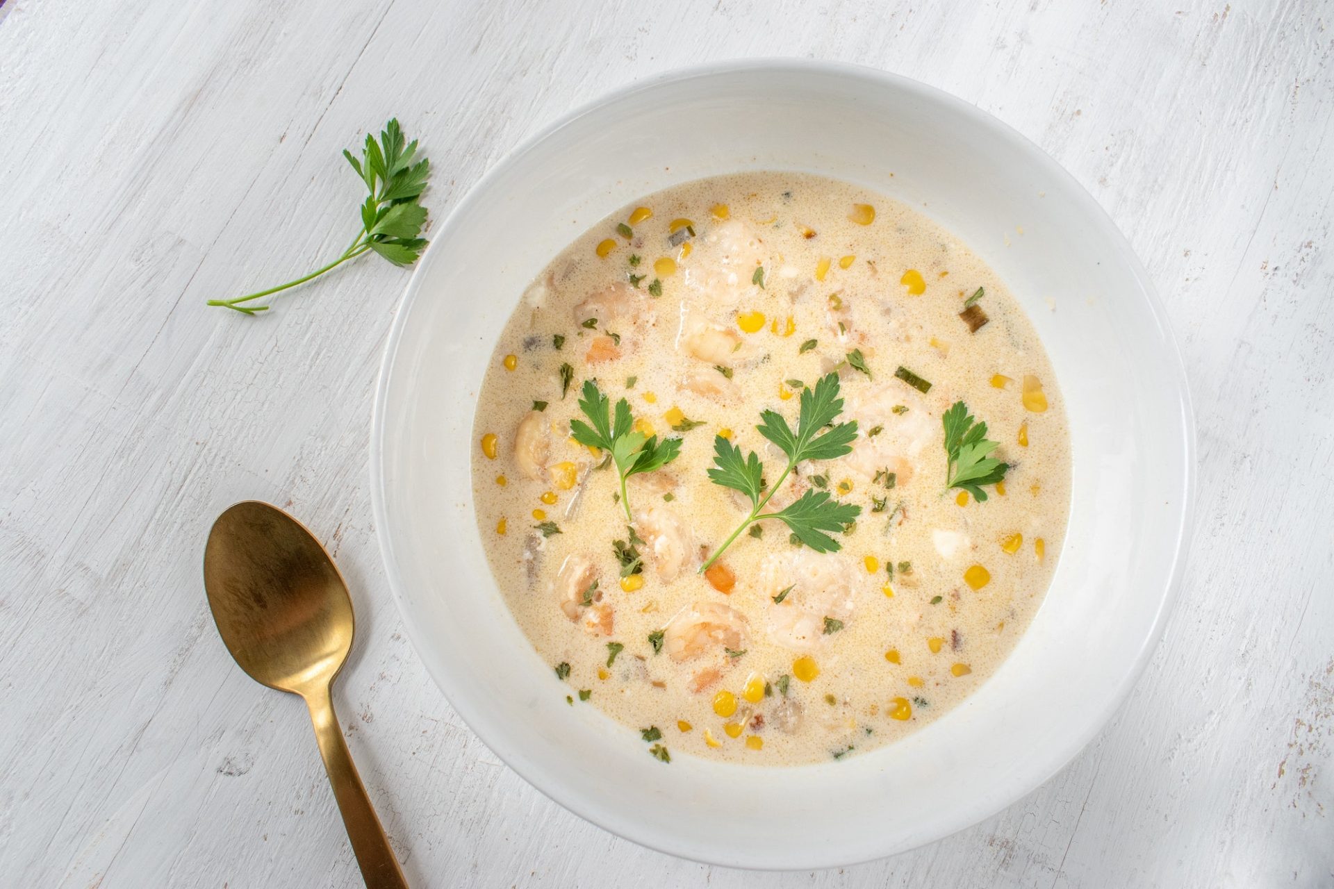 creamy seafood chowder soup with corn and parsley flat lay
