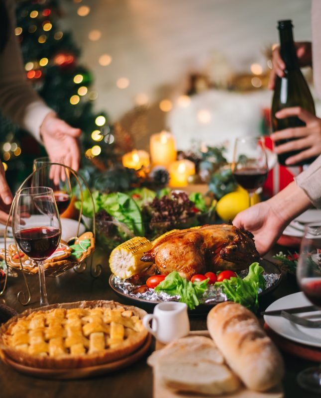 Close up Christmas or Thanksgiving dinner table infront of fireplace and xmas tree decorated at home