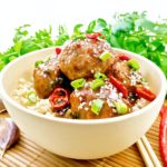 Meatballs in sweet and sour sauce with rice on wooden board