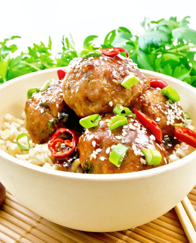 Meatballs in sweet and sour sauce with rice on wooden board